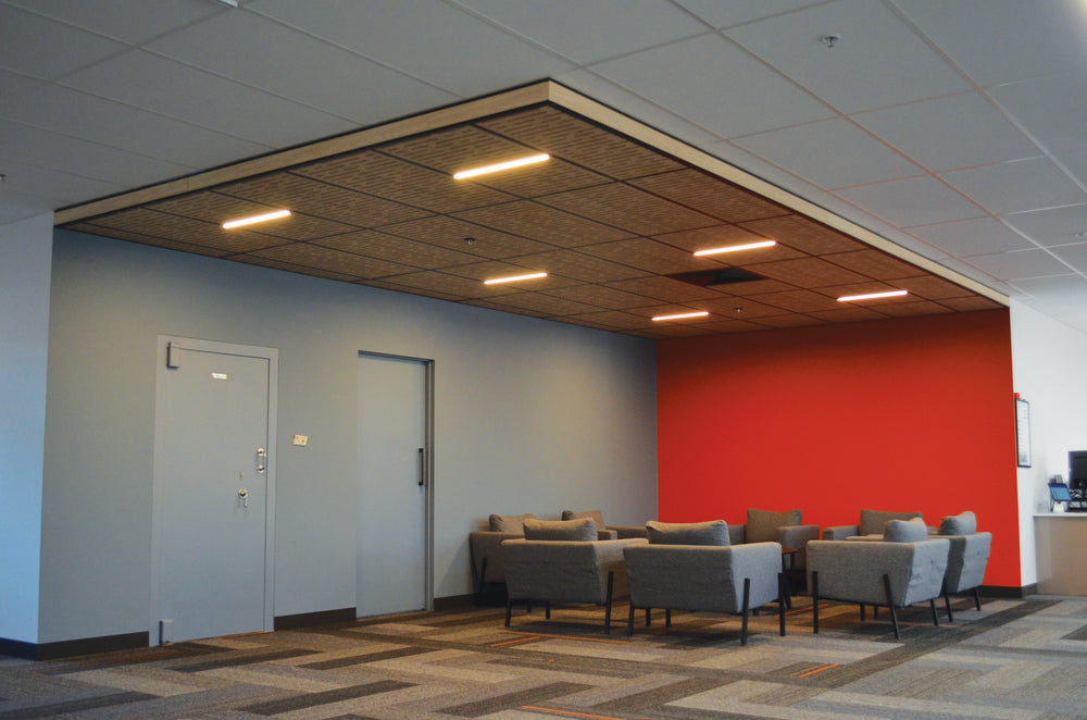 Modern office waiting area with red accent wall, gray chairs, and white doors.