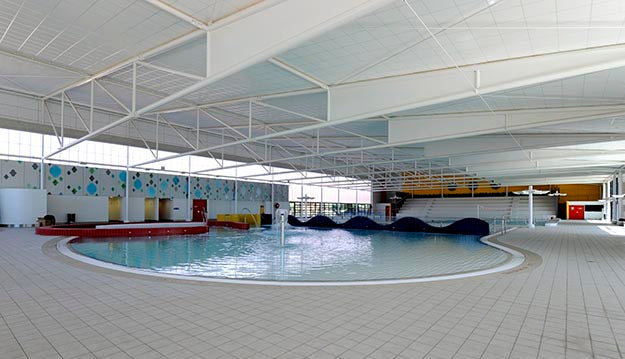 Large indoor pool with tiled floor and white ceiling
