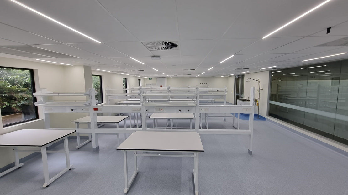 Modern laboratory with white tables and benches, large windows, and a clean layout.