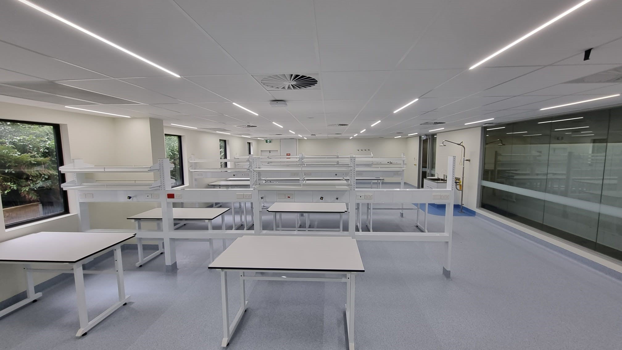 Modern laboratory with white tables and benches, large windows, and a clean layout.