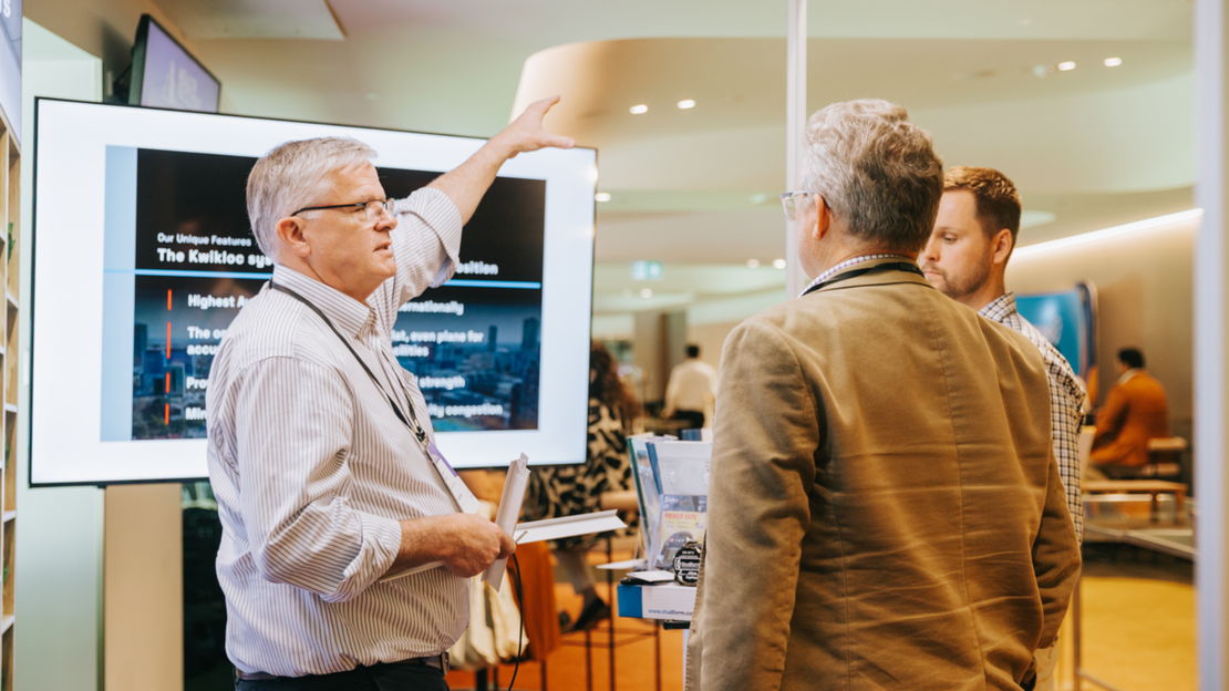 Two men interacting with a large screen displaying a presentation in an office setting.