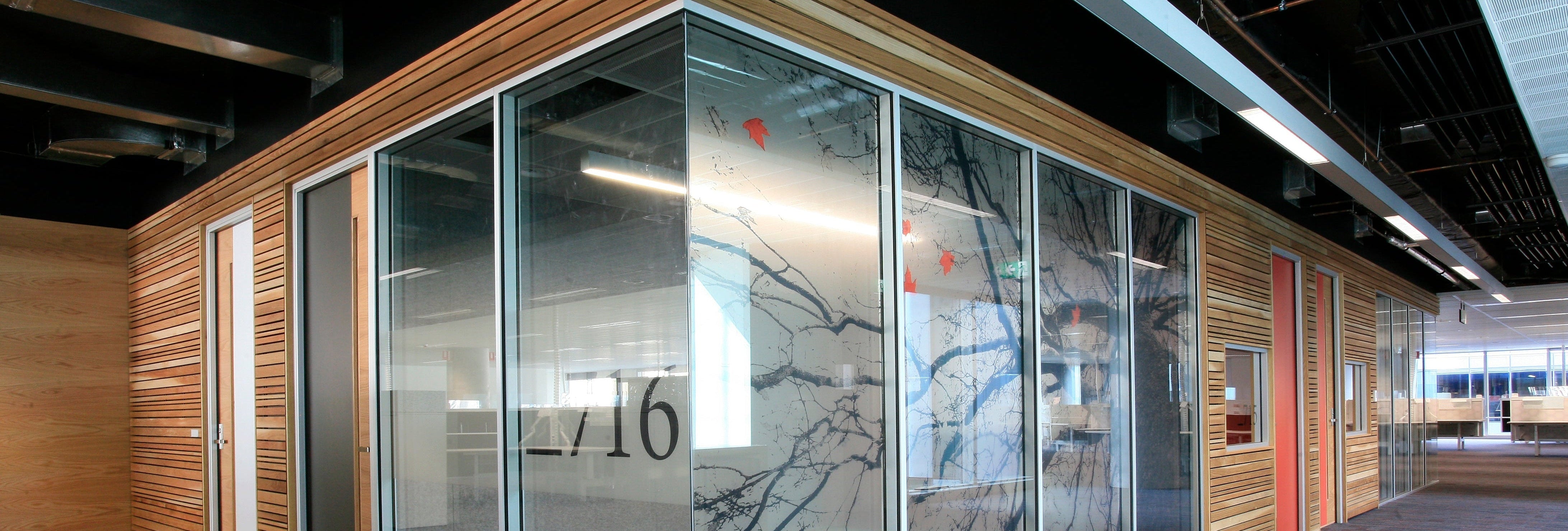 Modern office space with glass-walled partition and wooden panels.