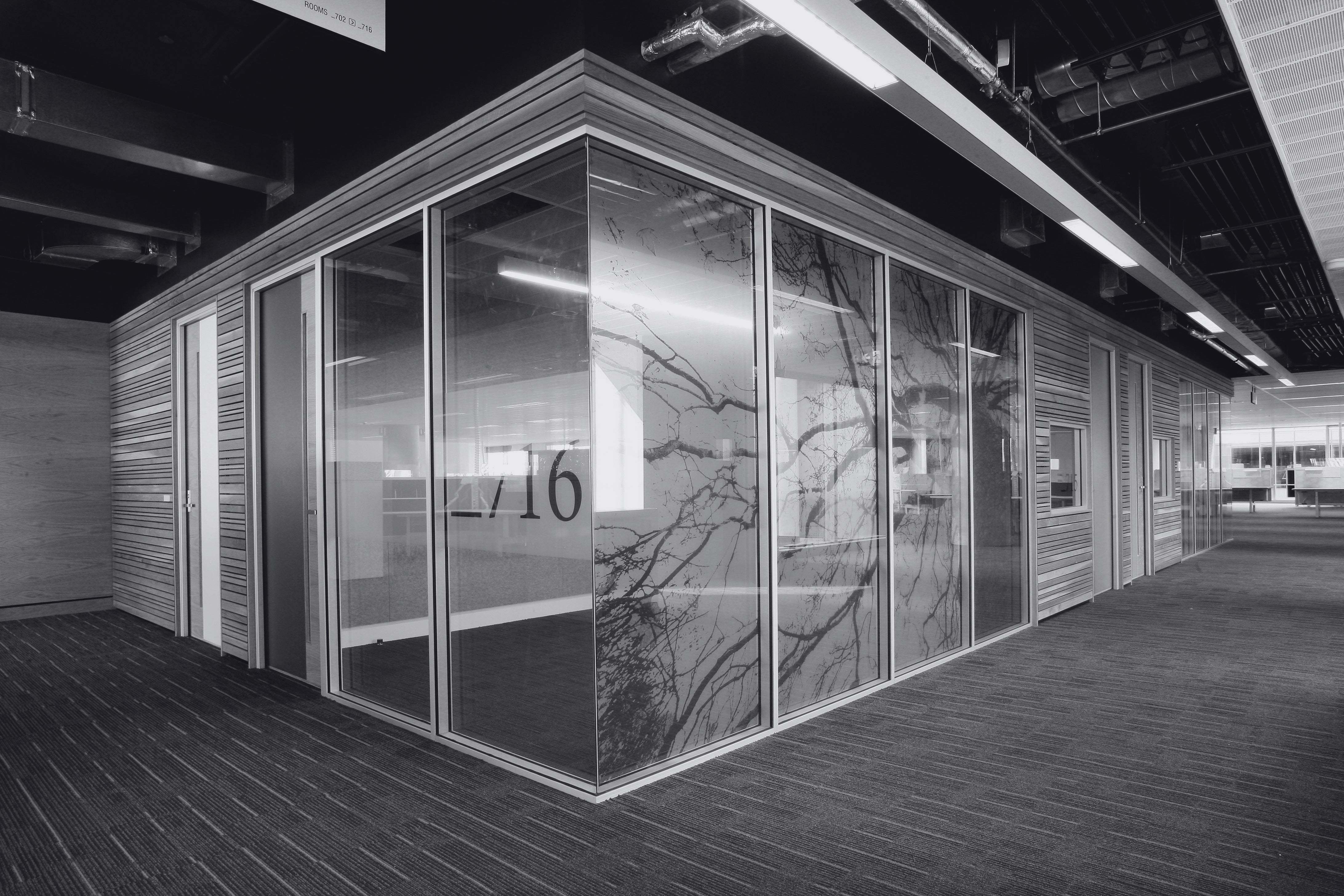 Modern office space with glass-walled partition and number 1716 on a wall.